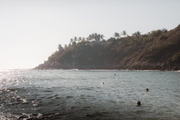 Beach Scenery - Peaceful ocean view with swimmers near a rocky c #15941830