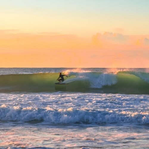 Beach Scenery - A surfer enjoys a thrilling ride on a wave durin #16354188