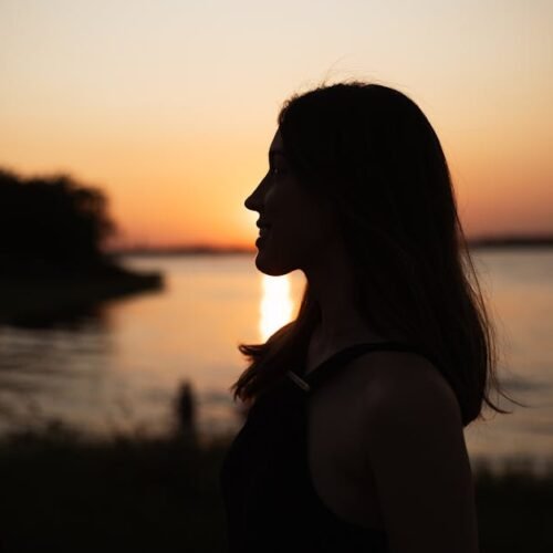 Lake Reflections - A serene silhouette of a woman standing by a lak #28051886