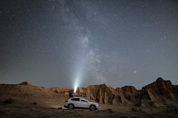 Desert Wilderness - A person stands on an SUV under a vast starry ni #3064258