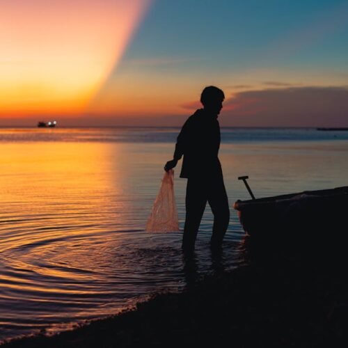 Beach Scenery - A silhouette of a fisherman with a boat at sunse #31621071