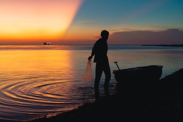 Beach Scenery - A silhouette of a fisherman with a boat at sunse #31621071