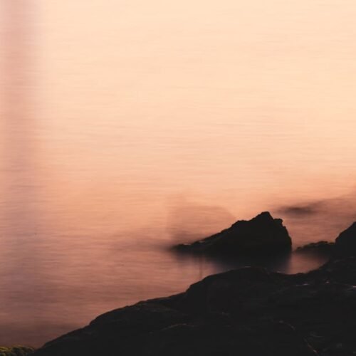 Desert Wilderness - Soft focus image of rocks by the calm sea at sun #32903576