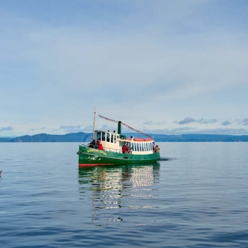 Lake Reflections - A vibrant boat on the serene waters of Lake Taup #33108417