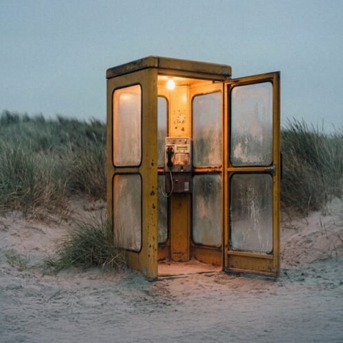 Beach Scenery - An illuminated vintage phone booth stands alone  #35639899