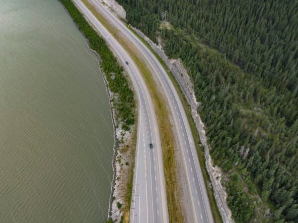 Lake Reflections - Drone shot of a winding road flanked by lush for #7054809