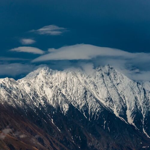 Snow Mountains - Scenic view of a snow-capped mountain under a cl #8119607