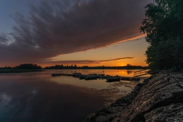 Lake Reflections - Calm lakeside at sunset with a dock silhouetted  #9245120